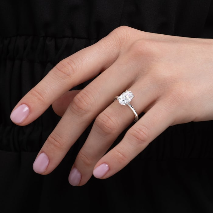 Hand wearing a diamond ring on a black background