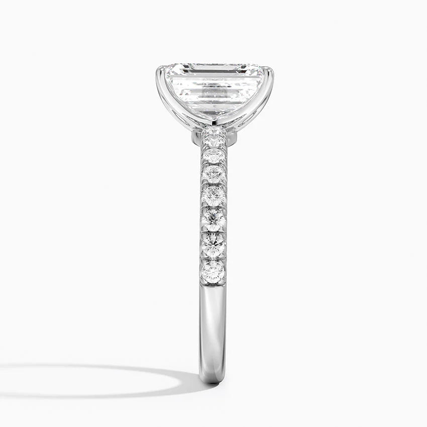 Diamond ring with a rectangular center stone and smaller stones on the band against a white background